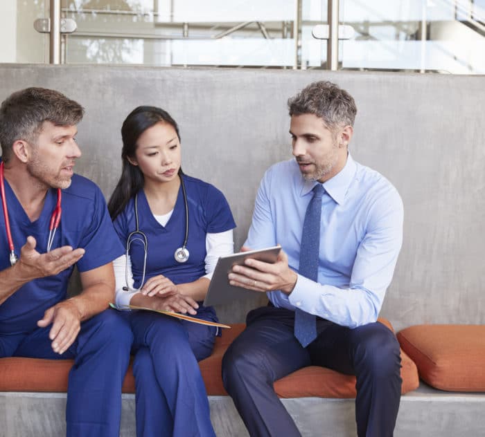 Healthcare workers in discussion using a tablet computer