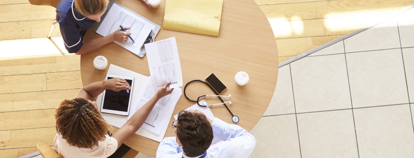 Three senior healthcare workers in a meeting, overhead view