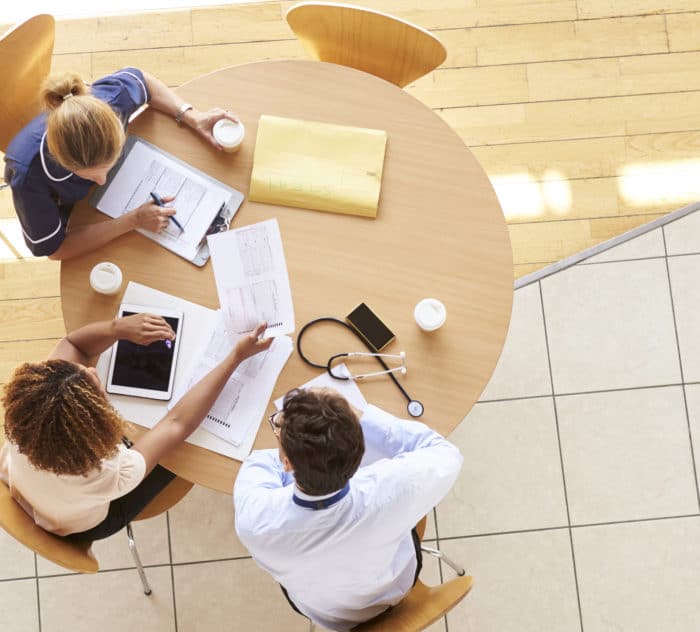 Three senior healthcare workers in a meeting, overhead view