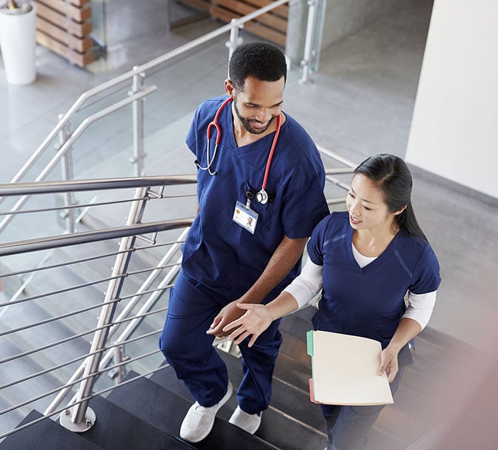 Two healthcare colleagues talking on the stairs at hospital